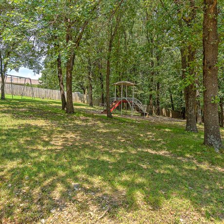 play structure on grass surrounded by trees